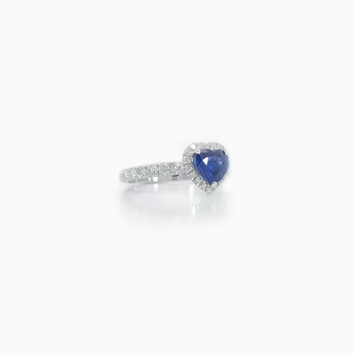 Heart-shaped blue sapphire ring with a diamond halo and pavé-set white gold band.