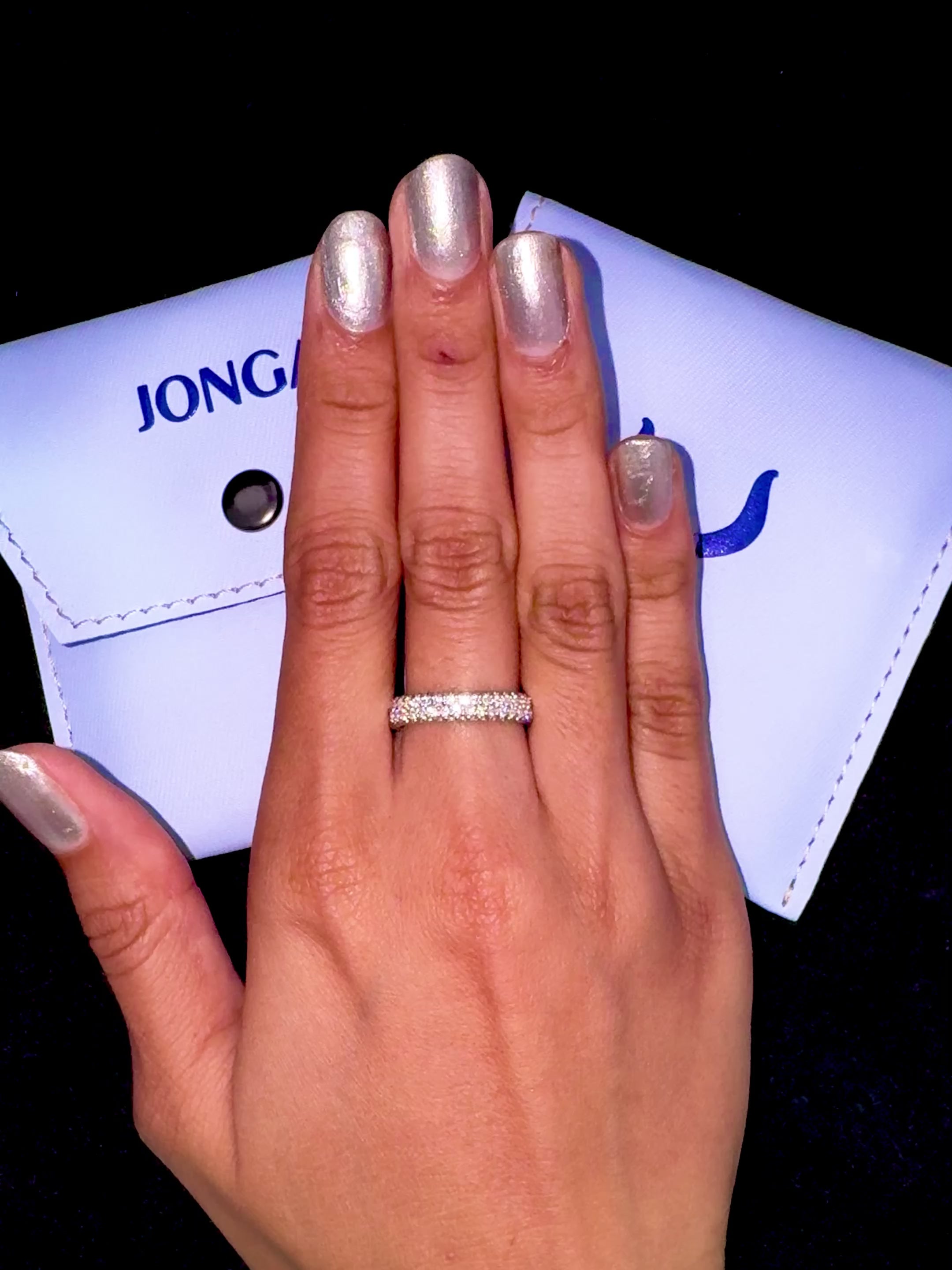 Captivating white gold 4-row diamond band elegantly worn on her finger, featuring up to 2.10 carats of meticulously arranged micro diamonds. This iconic design, known globally as an eternity band, classic pave band, multi-row diamond band, and refined diamond band, showcases a shimmering icy gold luster with intricate engravings and graceful contours. The image blends feminine allure with contemporary luxury and timeless elegance. Keywords: white gold, diamond band, micro diamonds, chic.